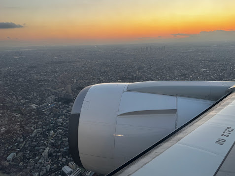 夕暮れの街上空を飛ぶ飛行機のエンジン